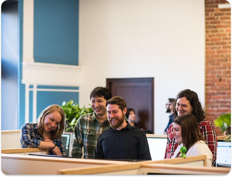 built mighty team smiling over a computer in cubicle area