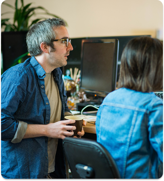 built mighty team at desk, employee holding cup of coffee looking at computer